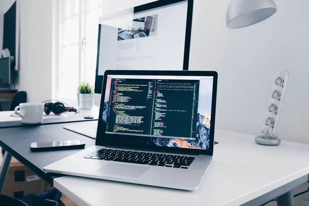 Laptop showing website code on a developer's desk
